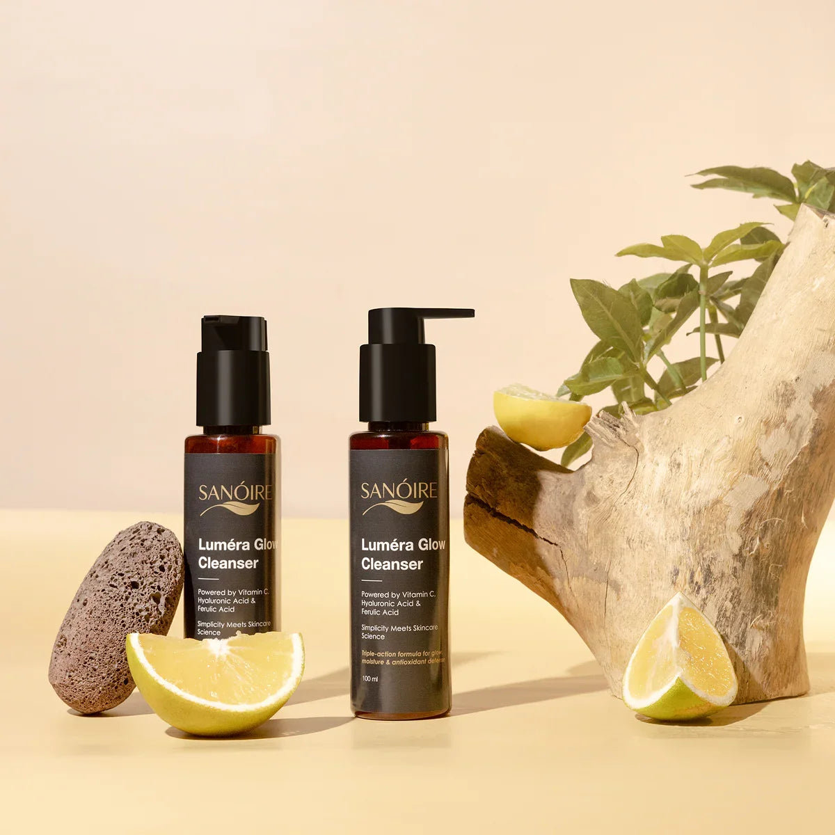 Luméra Glow Cleanser skincare bottles with lemon, pumice, and wooden decor on neutral background