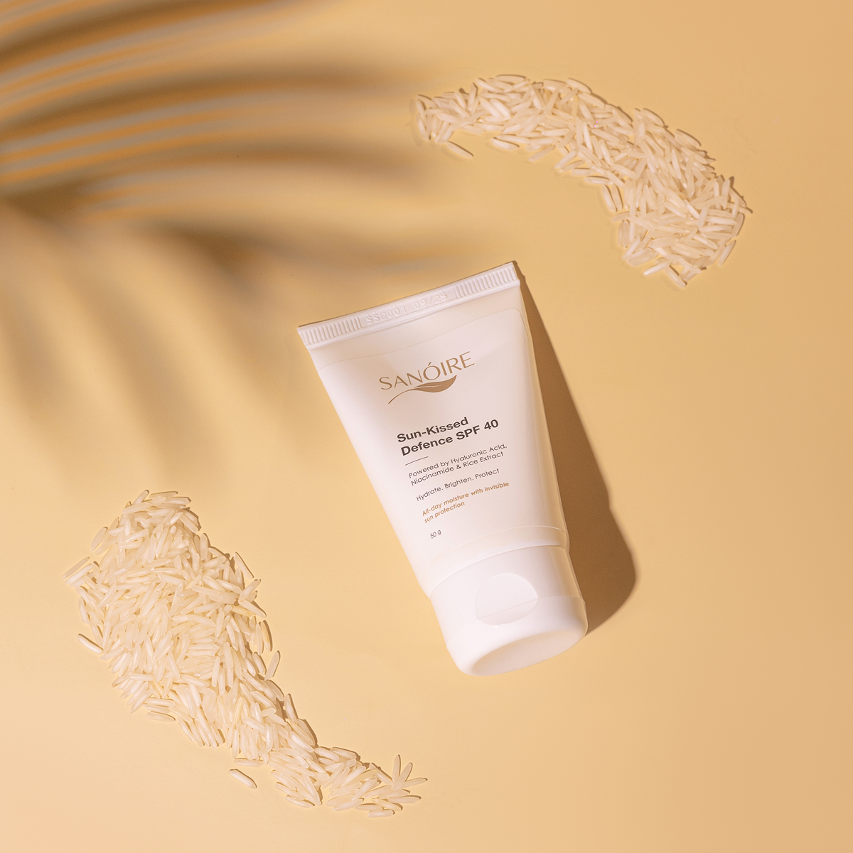 SPF 40 sunscreen tube on beige background with rice grains and palm leaf shadow