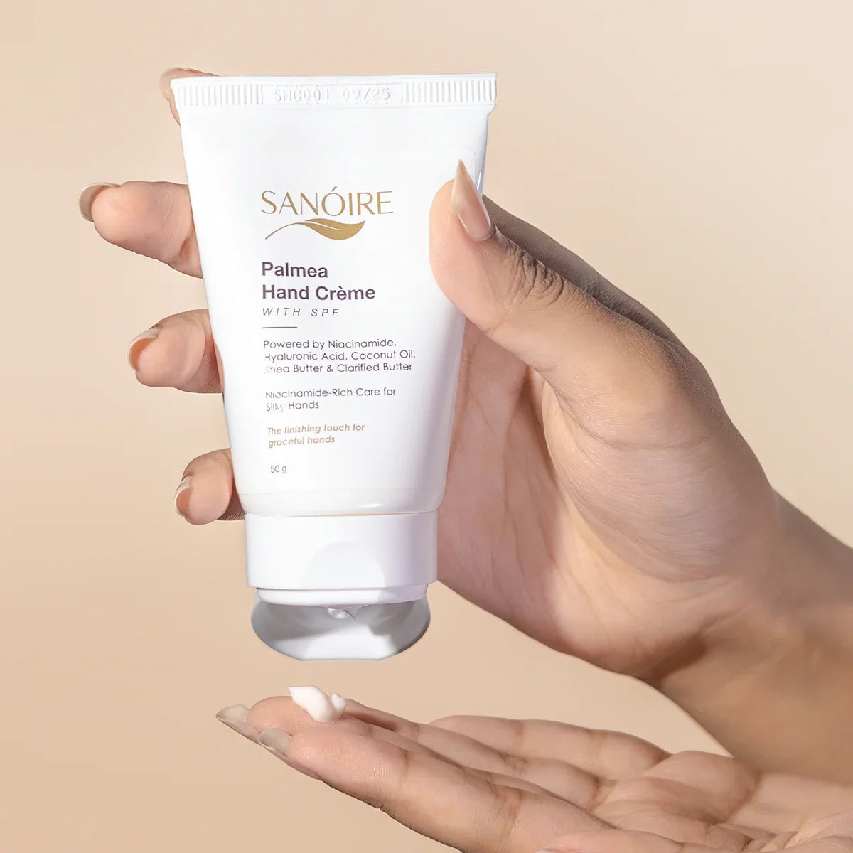 Hand holding Palmea Hand Crème with SPF, dispensing moisturizing cream onto palm