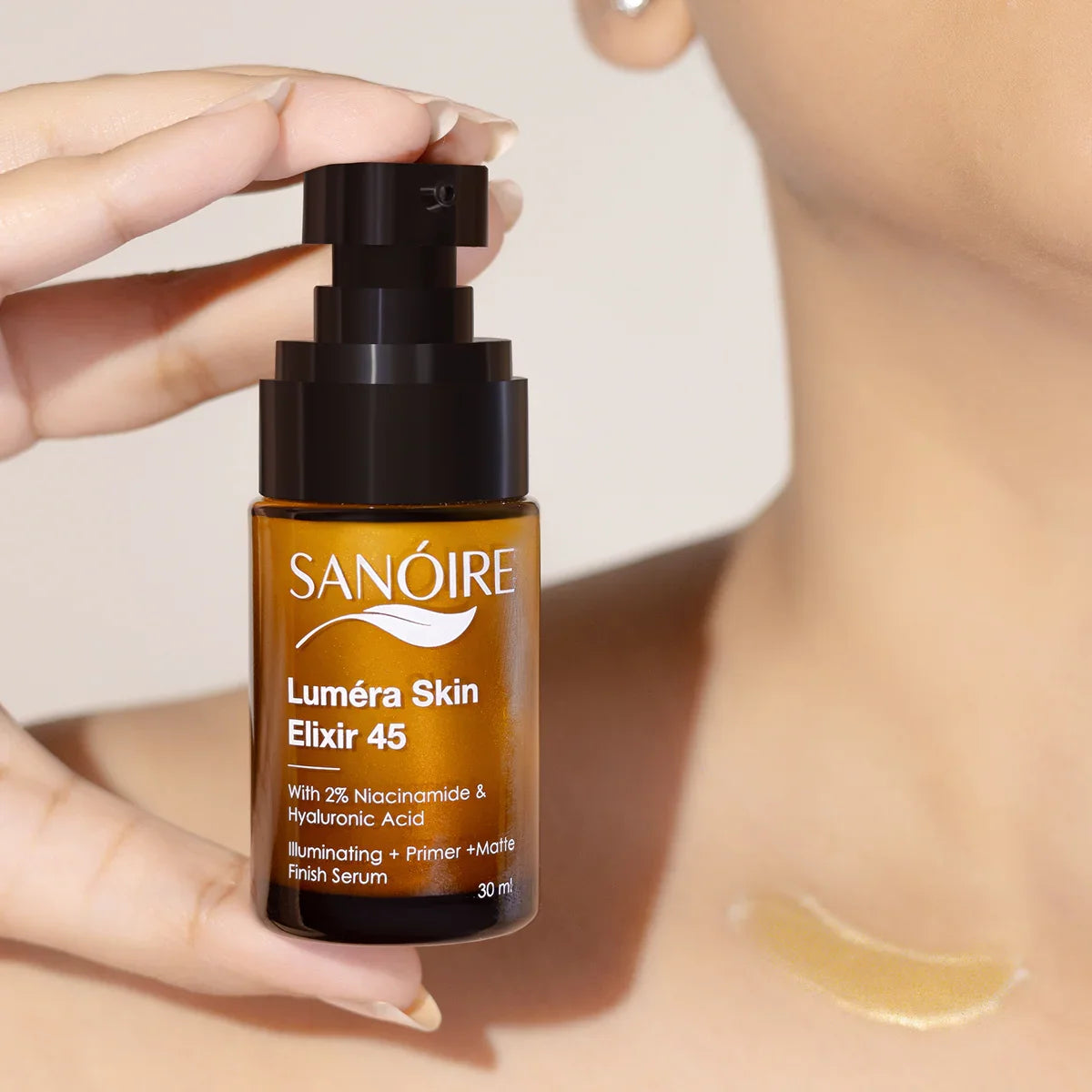 Hand holding Luméra Skin Elixir 45 serum bottle, swatch on model’s neck, skincare product