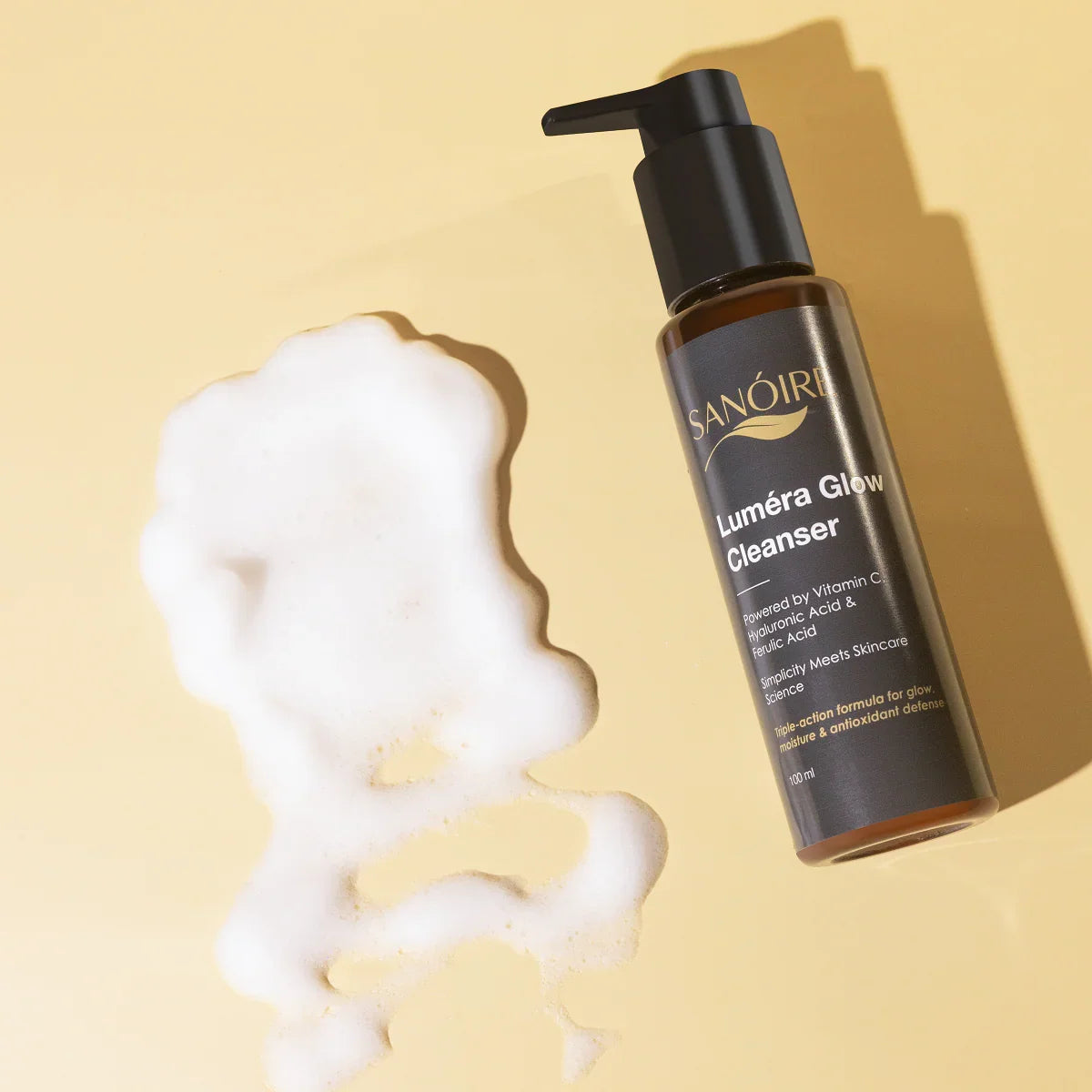 Luméra Glow Cleanser bottle with foam, skincare product on beige background