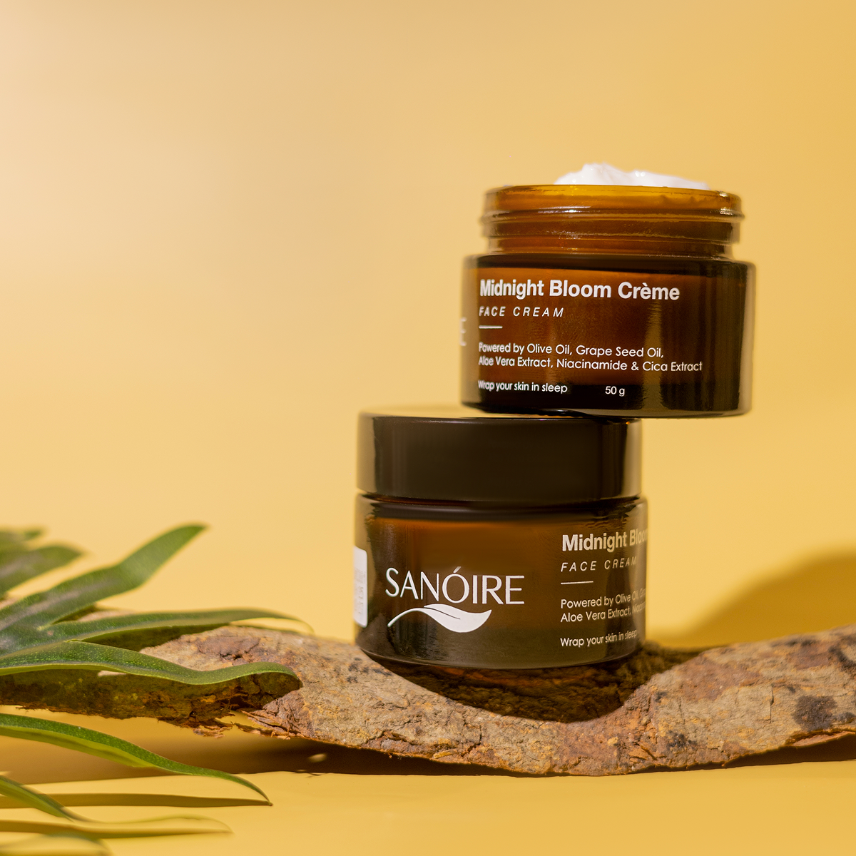 Amber jars of Midnight Bloom Crème face cream with natural ingredients on yellow background.