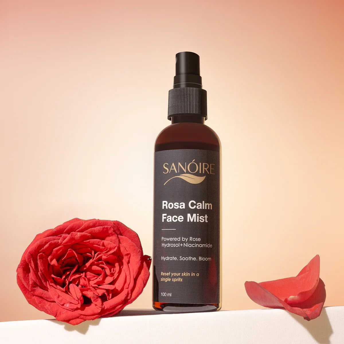 Rosa Calm Face Mist bottle with rose hydrosol and niacinamide beside red rose and petals
